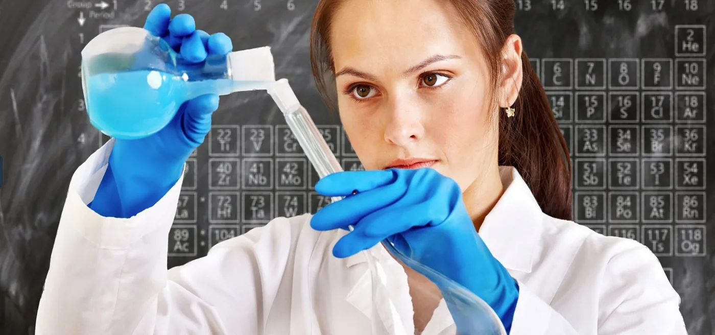 Ricercatrice in laboratorio davanti alla tavola periodica